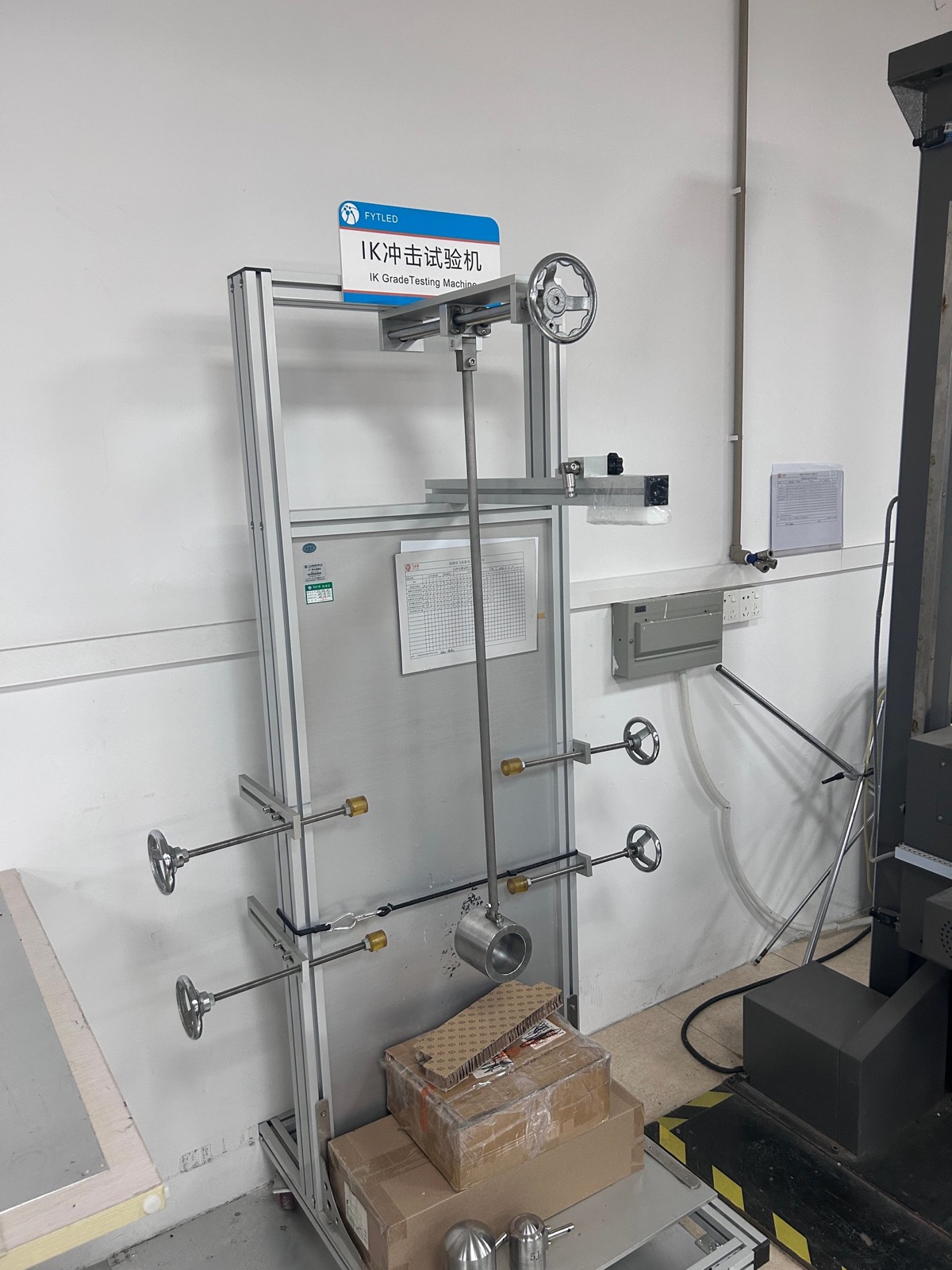 IK impact test rig with drop hammer verifying IK08 impact resistance on LED luminaire housing and lens